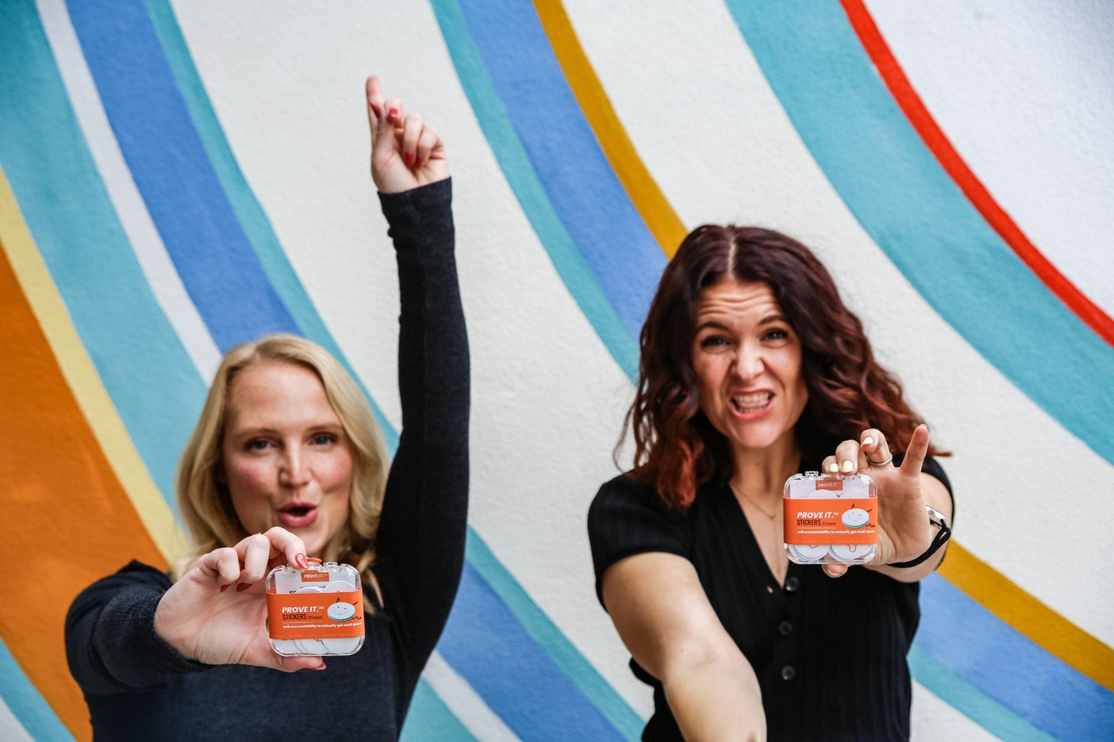 The shelpful co-founders pointing at the camera, holding PROVE IT cases