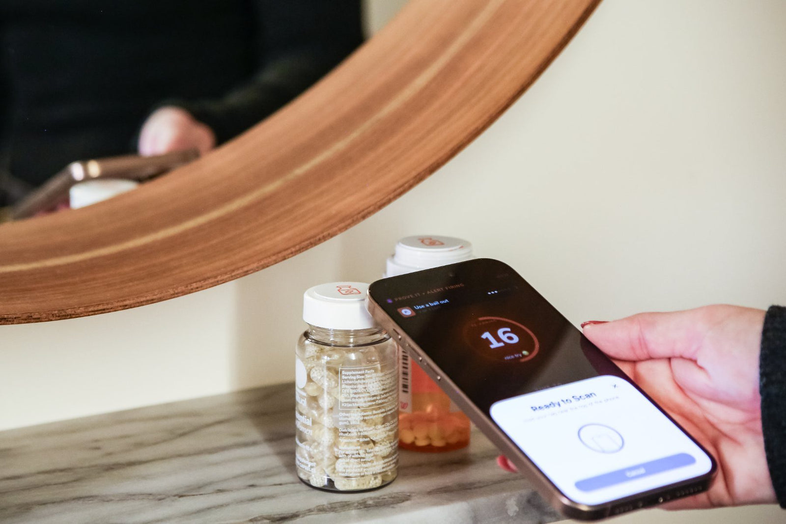 Tapping the meds sticker on a pill bottle under the bathroom mirror